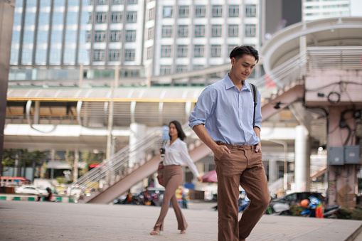 A young businessman confidently walks in the downtown district on his way to his office.