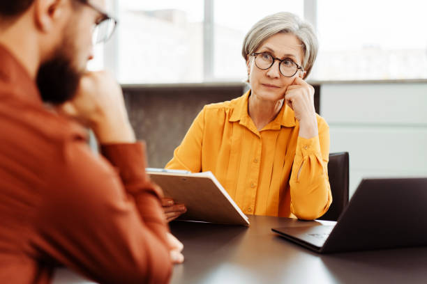 Serious senior woman, psychologist listening patient. Therapy, psychologist session, mental health Serious senior woman, psychologist listening patient, looking for solution in modern office. Therapy, psychologist session, mental health concept grave stock pictures, royalty-free photos & images
