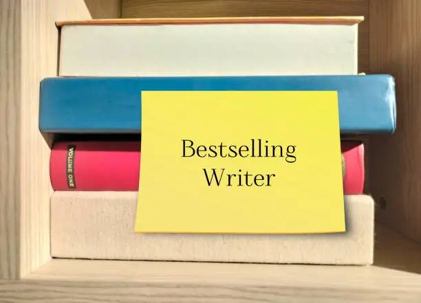 Photo of Books with stick note on the side written BESTSELLING WRITER, refers to a successful author or passionate , goat setting writer who aim to be one