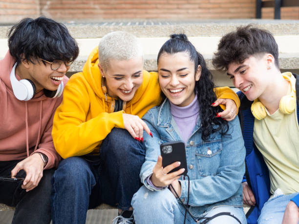 Group of young people smiling while looking at the mobile phone. Social networks and generation z, young millennials