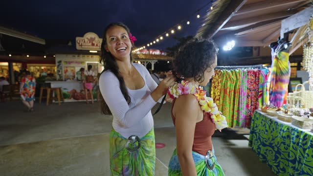 Woman puts lei necklace on friend
