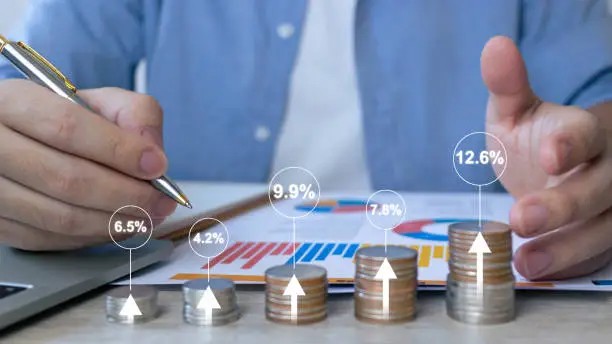 Photo of Interest rate and dividend concept.Businessman stacking coins and calculating with percentage for interest rating. Investor, trader, investment, fund and stock market.