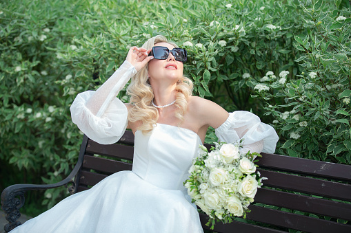 a blonde girl in a wedding dress and with a hairstyle, a bride with a bouquet of white flowers, a holiday