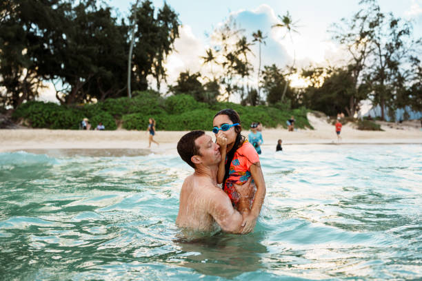 istock Father holds young daughter in the ocean 1891413246