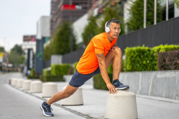 Athletic mature man stretching leg on street.