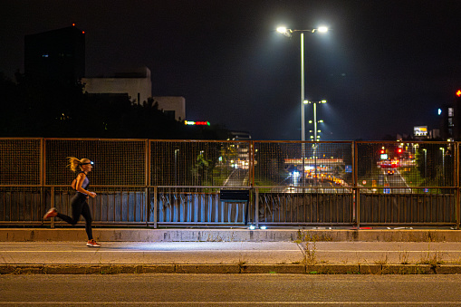 Young woman running in city above on highway at night.