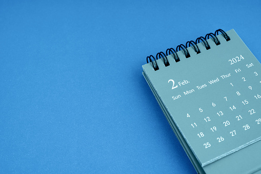 February 2024 desk calendar on blue color background. Copy space.