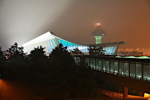 Sterling, Virginia, USA - December 27, 2023: Floodlights shining on the Main Terminal at Washington Dulles International Airport reflect off the surrounding fog that has descended on the well-known landmark in Northern Virginia.