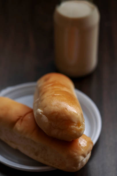 istock Bread on a white plate sits on a wooden board table with milk in a bottle behind it 1891513168