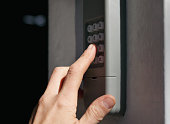 Person using garage door keypad or keyless door access number pad.