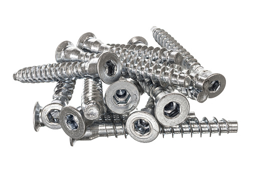 A heap of silver-colored screws with hex heads isolated on a white background.