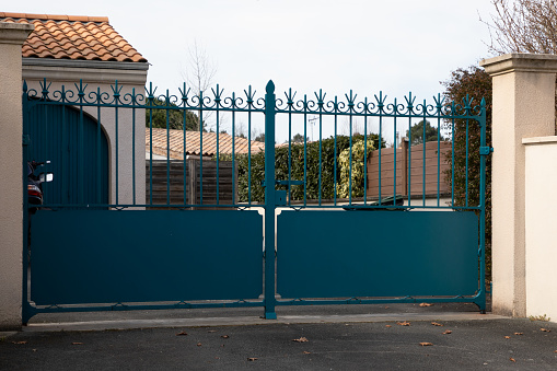 Calgary, Alberta, Canada- July 16,2022:  Large gate across driveway that leads up to home. Stone pillars on either side. Xeriscaped landscaping at side of gate and driveway.