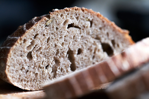 Homemade whole meal spelt bread with sunflower seeds and baking ingredients on wooden background