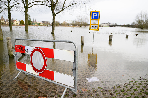 Deventer at the river IJssel with high water level after heavy rainfall upstream in Germany in December 2023. The park and parkinglot at the Worp is flooded, but people are still crossing the road towards the ferry to the city.