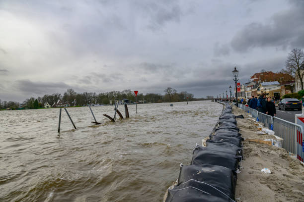 Deventer at the river IJssel with high water level after heavy rainfall upstream in Germany in December 2023. People are looking at the river and the temporary sand bag barrier on the quay.
