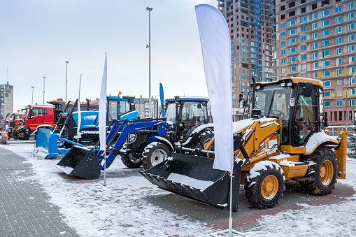 Two wheeled tractors, a bulldozer and snow removal equipment at an industrial exhibition in winter
