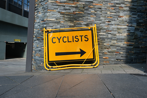 The direction metal sign on a footpath showing the direction that cyclists should take.