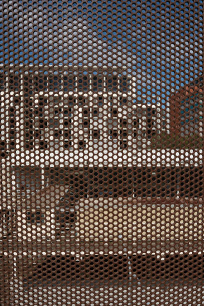 Looking through a brown perforated metal sheet with buildings beyond.