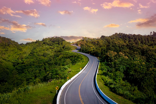 The sunset view with  highway stairs to the sky of road trough with green forest  as the nature landscape background