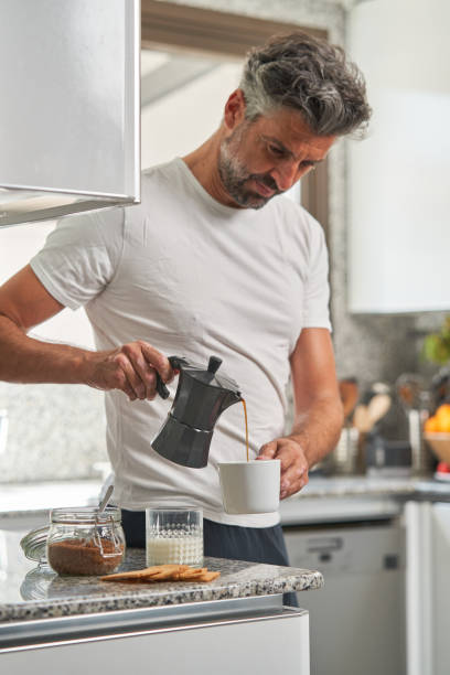 istock Serious man pouring coffee from moka pot in kitchen 1891757071