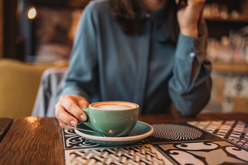 Close-up image of an unrecognizable female person drinking a cup of coffee