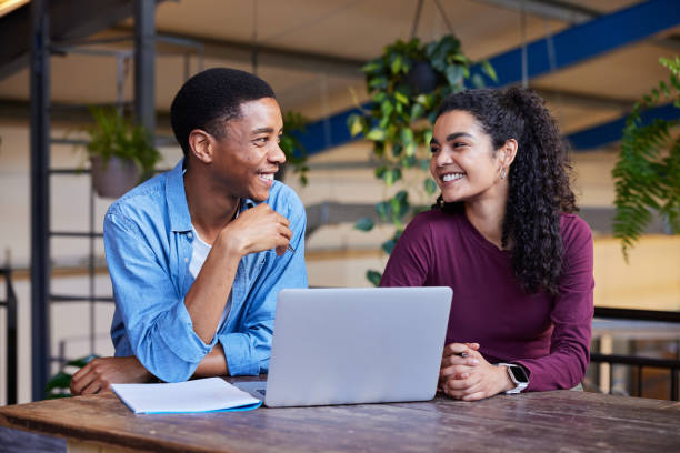 istock Smiling college students doing homework on a laptop in a campus lounge 1891833616