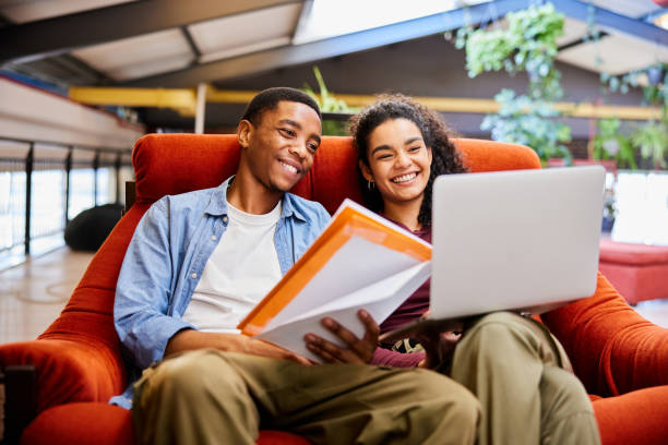 istock College students smiling while doing homework in a chair in a campus lounge 1891839429