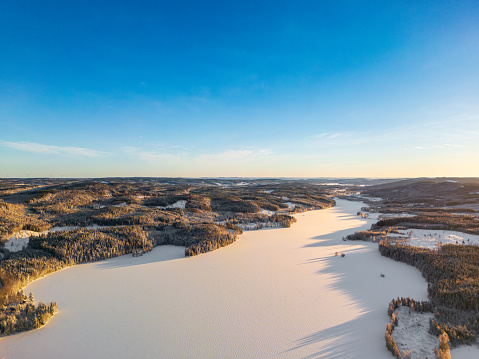 Aerial panoramic photo of a Swedish landscape , lake, cold sunny day, blue sky, wild northern subarctic nature, winter time, wild birch forest, Sweden