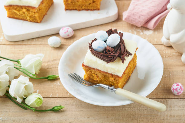 istock Easter carrot cake bars decorated with chocolate nest and chocolate candy eggs blossoming cherry or apple flowers on rustic light wooden backgrounds. Easter holiday meal. Traditional Easter food. 1891840520