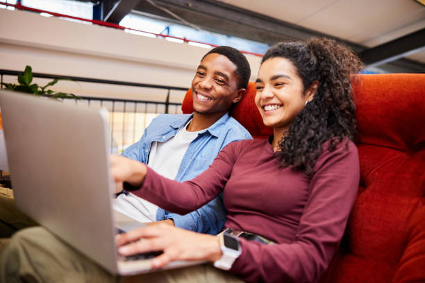 istock Two college students smiling and doing homework in a campus lounge 1891841646