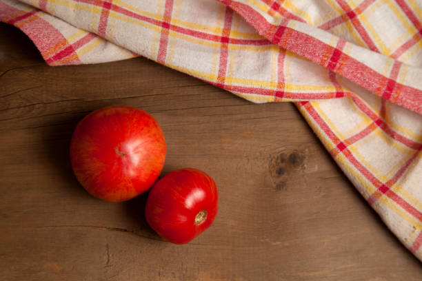 istock Red tomatoes and red towel on wooden background. 1891893202