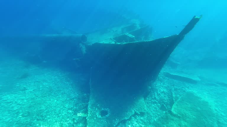 Boy with diving mask pointing to a sunken ship at the bottom of the sea