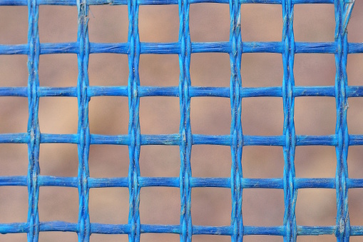 texture of part of a blue plastic lattice on a brown background