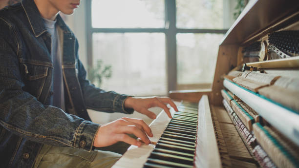 istock Male student practicing piano lessons and playing classical music on an old school open piano 1891913885