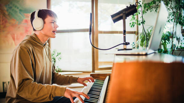 istock Male student wearing headphones practicing singing lessons and playing rap background music on the piano 1891914992