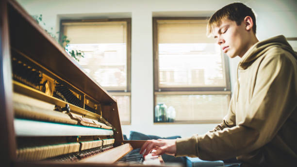 istock Male student practicing piano lessons and playing classical music on an old school piano. Hands pressing black and white keys 1891915569