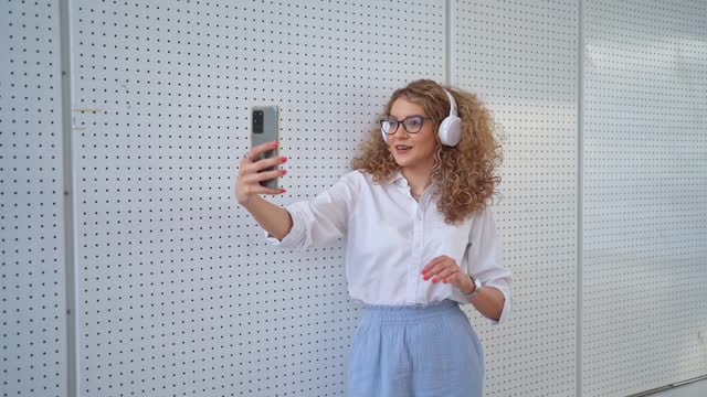 Young woman with curly hair talking on a video call using mobile phone