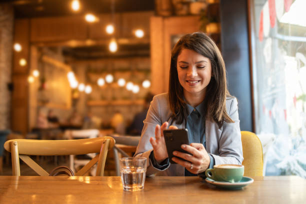 istock A woman reads a text message on a mobile phone in a coffee shop 1892039192