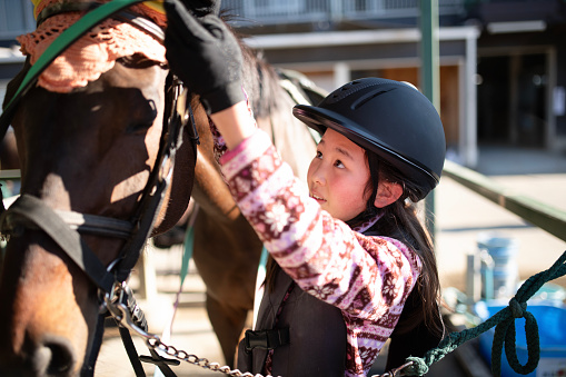 Kid girl adjusting stirrup for horse ride trip.