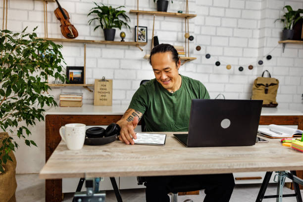 istock Smiling Chinese man using digital tablet in home office 1892077023