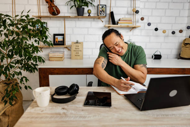 istock Smiling Chinese man writes notes during telephone call 1892078589