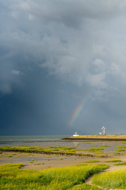 Heavy thunder clouds and a rainbow over the harbor entrance of the Dutch city of Terneuzen.