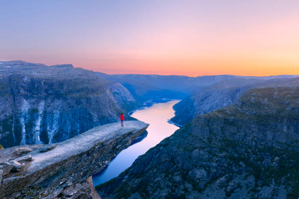 Alone tourist on Trolltunga rock - most spectacular and famous scenic cliff in Norway Alone tourist on Trolltunga rock - most spectacular and famous scenic cliff in Norway - Landscape geirangerfjord stock pictures, royalty-free photos & images