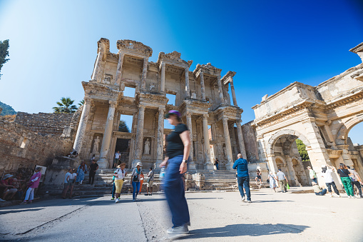 Tourists explore the famous Library of Celsus, a historic Roman building in Ephesus, Turkey, under a blue sky.