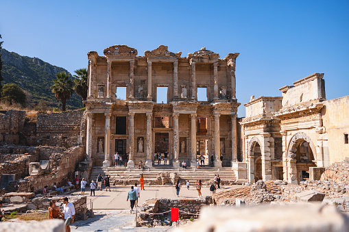 Tourists exploring the famous Library of Celsus, a historic Roman building in the ancient city of Ephesus, on a sunny day.