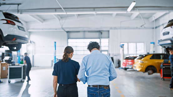 Auto Repair Shop Manager Having Discussion With A Skilled Woman Mechanic At Workshop