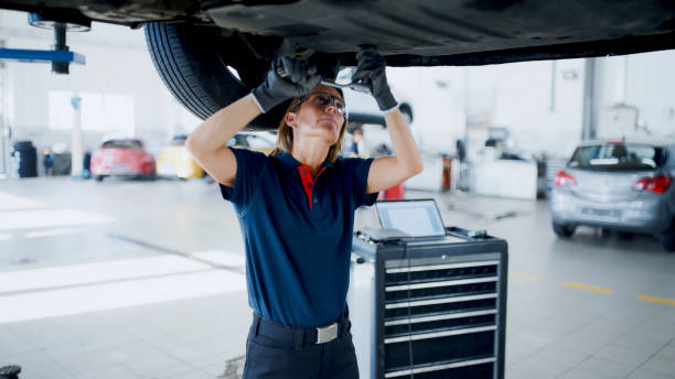 Female Mechanic Working Underneath Car In Auto Repair Shop Female Mechanic With Socket Wrench Working Underneath Car On Hydraulic Platform In Auto Repair Shop mechanic working under car stock pictures, royalty-free photos & images