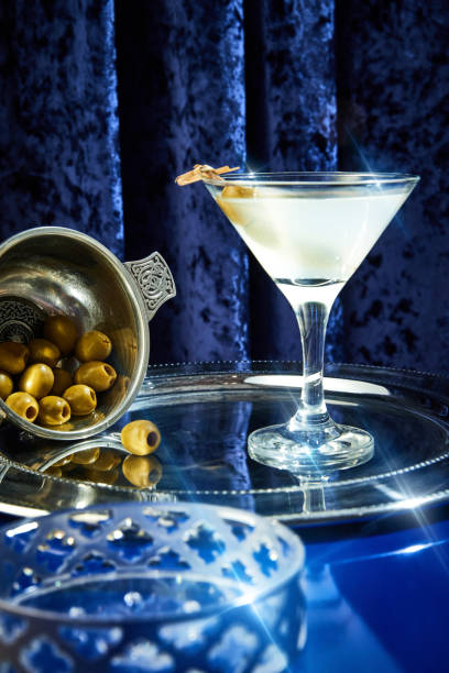 foto ravvicinata del classico martini secco in vetro a stelo seduto su vassoio d'argento guarnito con olive verdi in un ristorante di lusso. concetto di mood vacanziero. - martini brand vermouth foto e immagini stock