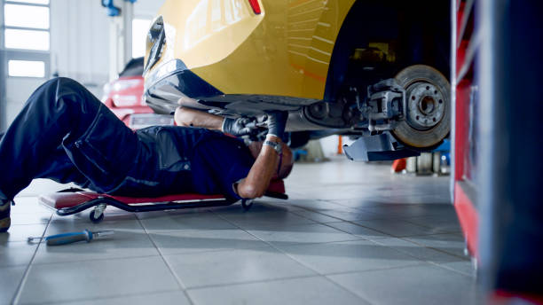 istock Male Mechanic On Creeper Working Under Car At Workshop 1892179624