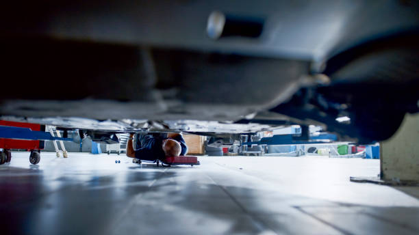 istock Male Mechanic On Creeper Working Under Car At Workshop 1892179626